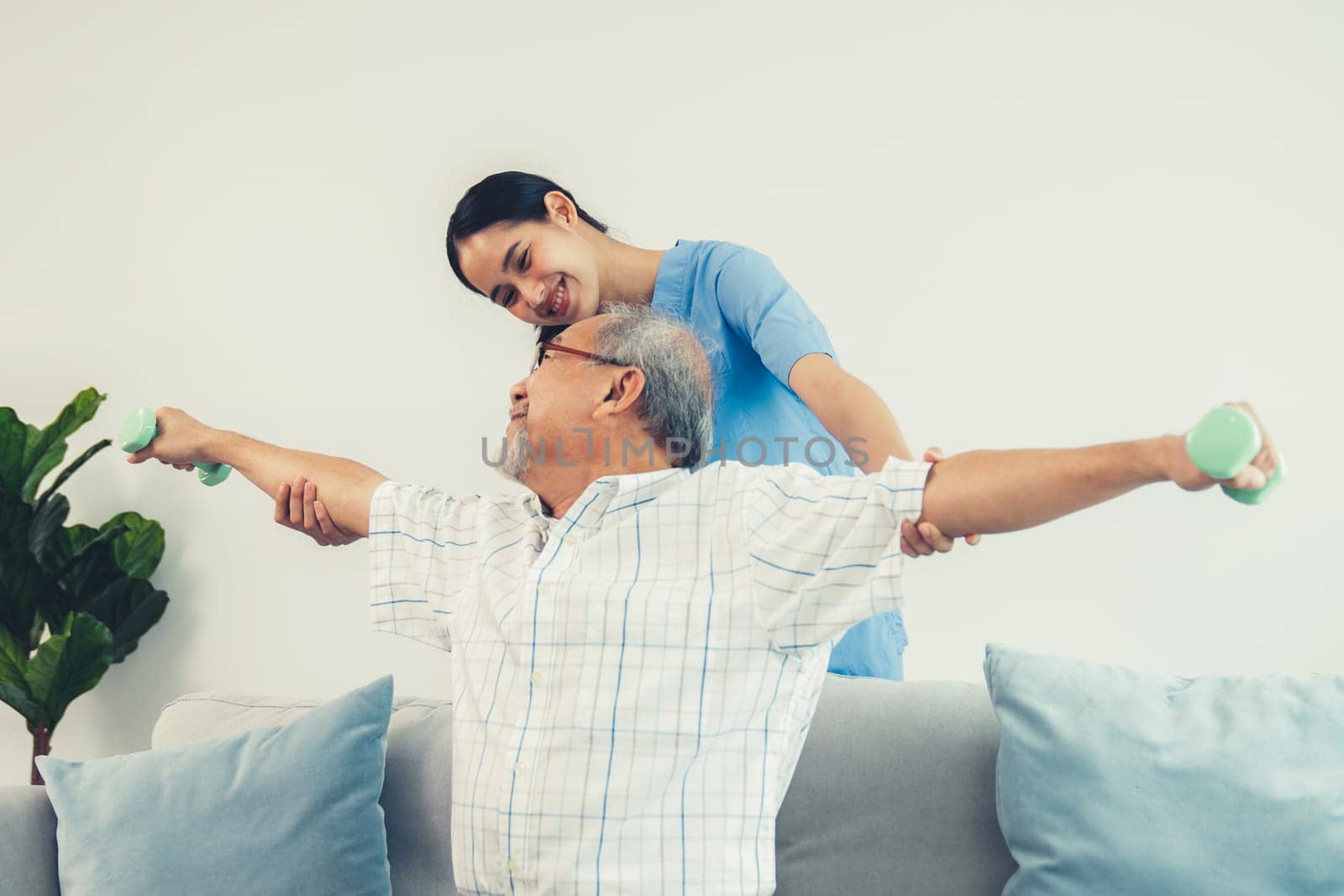 Contented senior patient doing physical therapy with the help of his caregiver. Senior physical therapy, physiotherapy treatment, nursing home for the elderly