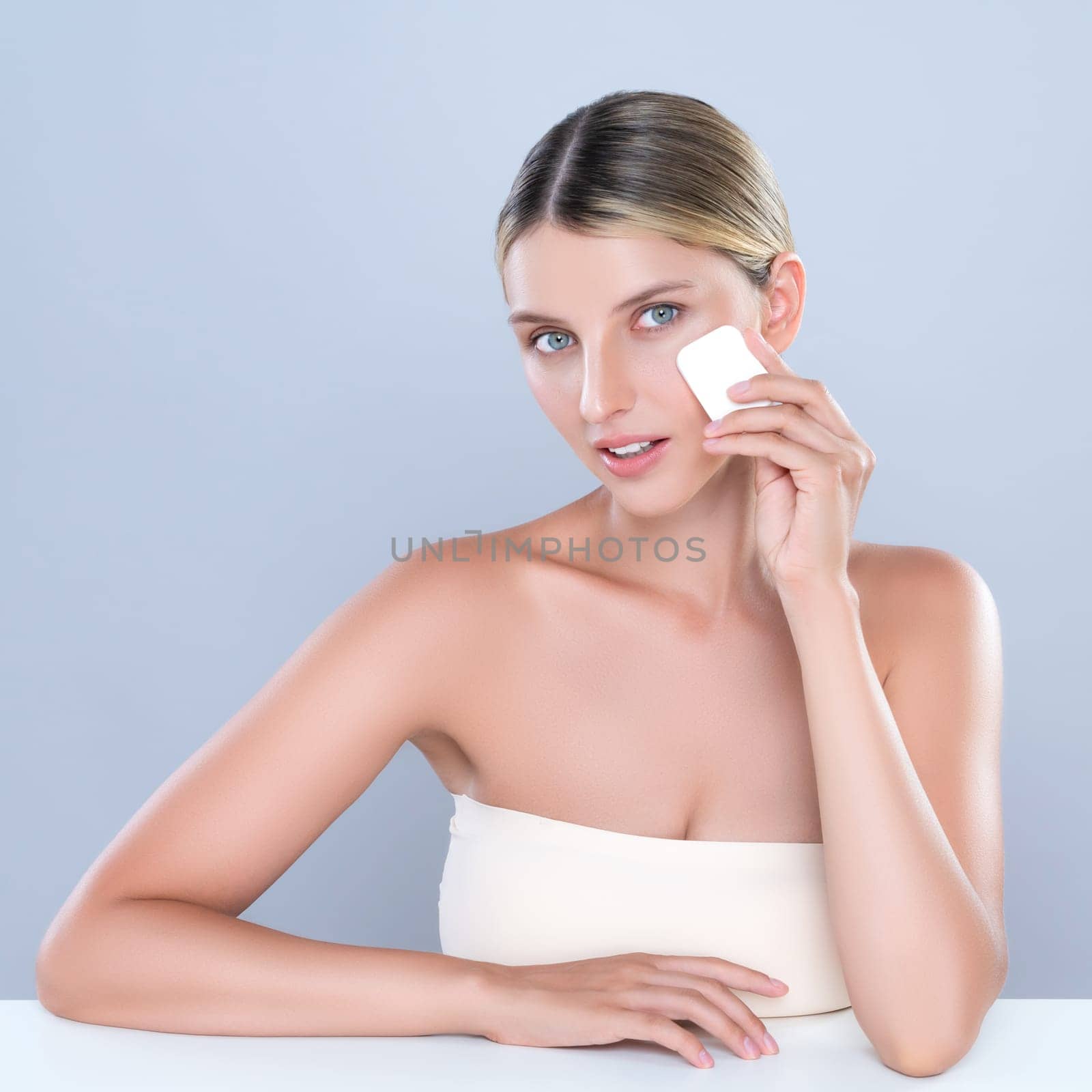 Alluring beautiful female model applying powder puff for facial makeup concept. by biancoblue