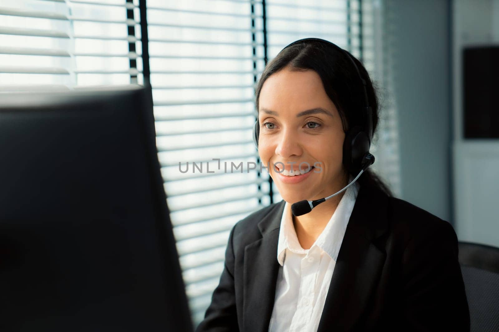 Competent female operator working on computer and talking with clients. Concept relevant to both call centers and customer service offices.