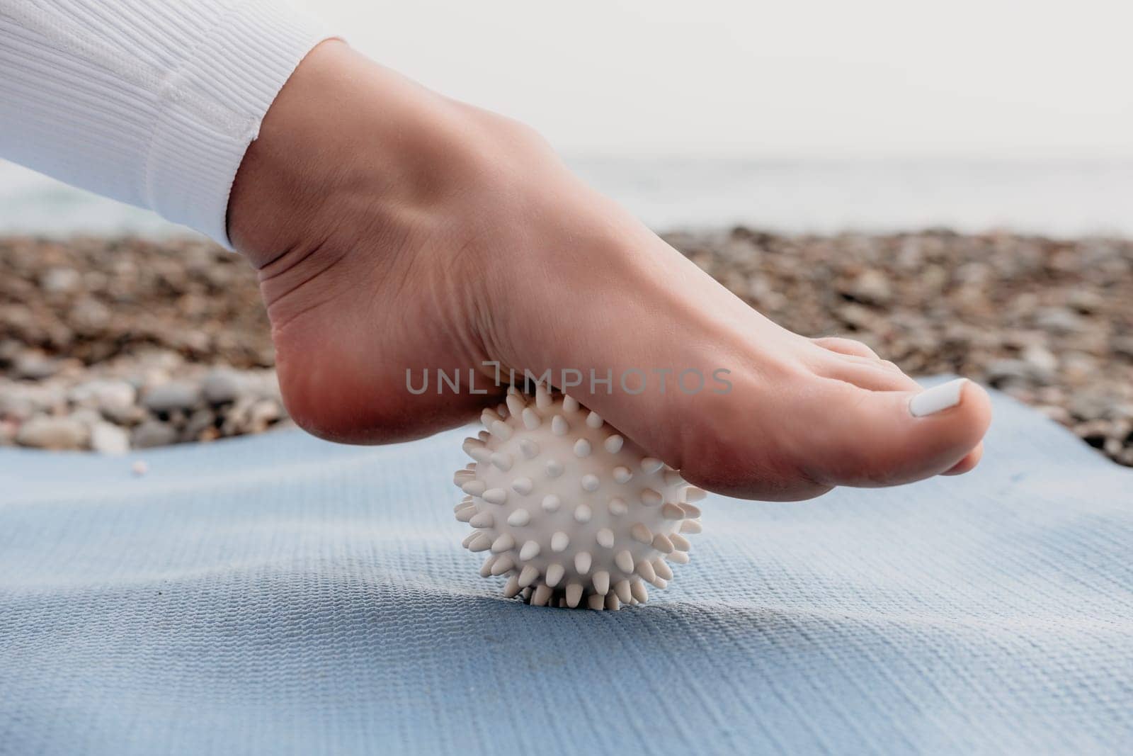 Woman yoga sea. Well looking middle aged woman with braids dreadlocks in white leggings and tops doing stretching pilates on yoga mat near sea. Female fitness yoga routine concept. Healthy lifestyle