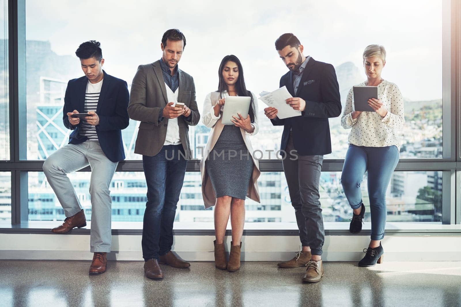Keeping busy and focused on success. a diverse group of businesspeople using wireless technology in an office