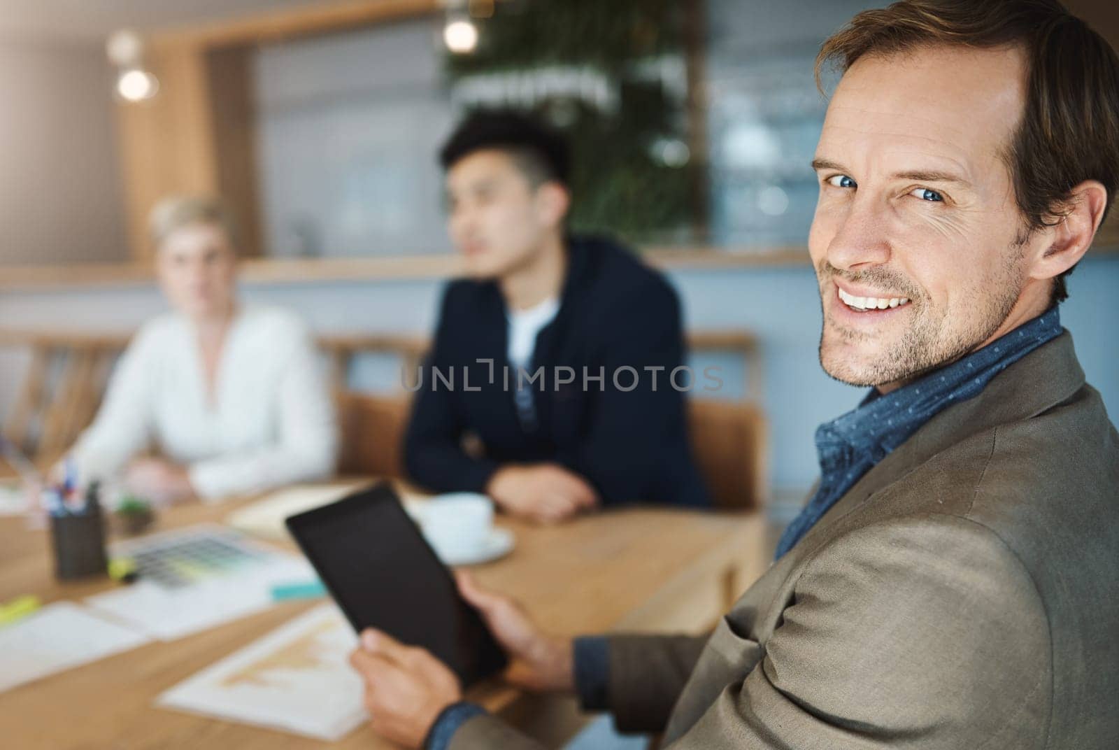 Im always taking down notes during our meetings. Portrait of a mature businessman using a digital tablet while in a meeting in an office