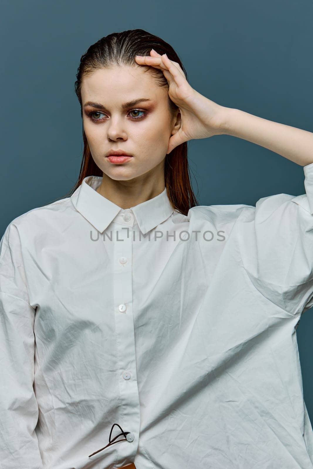 a beautiful, elegant woman with her hair laid back and evening makeup is standing in a light shirt looking to the side, holding her hand near her head by Vichizh