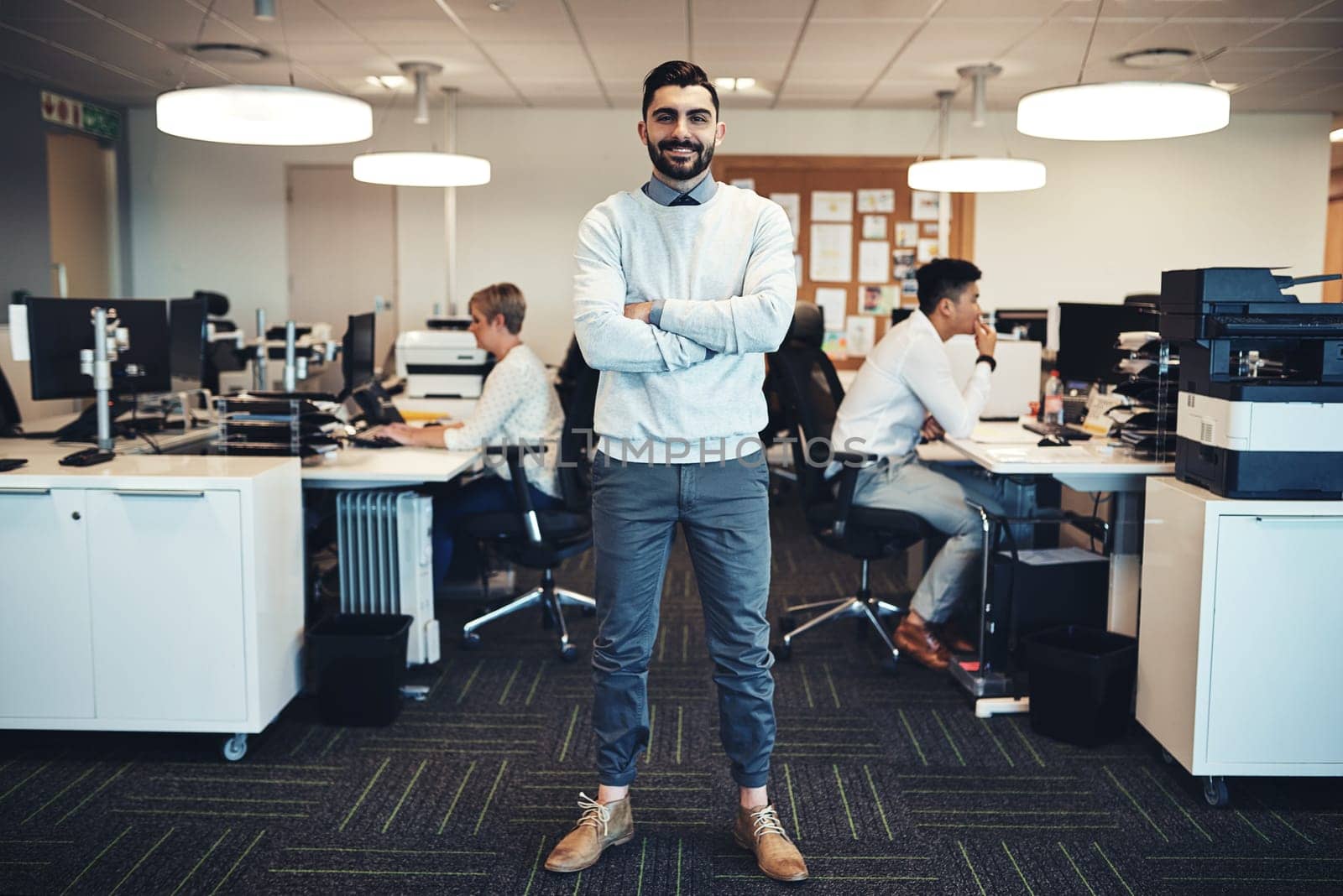 Love what you do and watch work prosper. Portrait of a businessman in the office while his colleagues are working in the background. by YuriArcurs