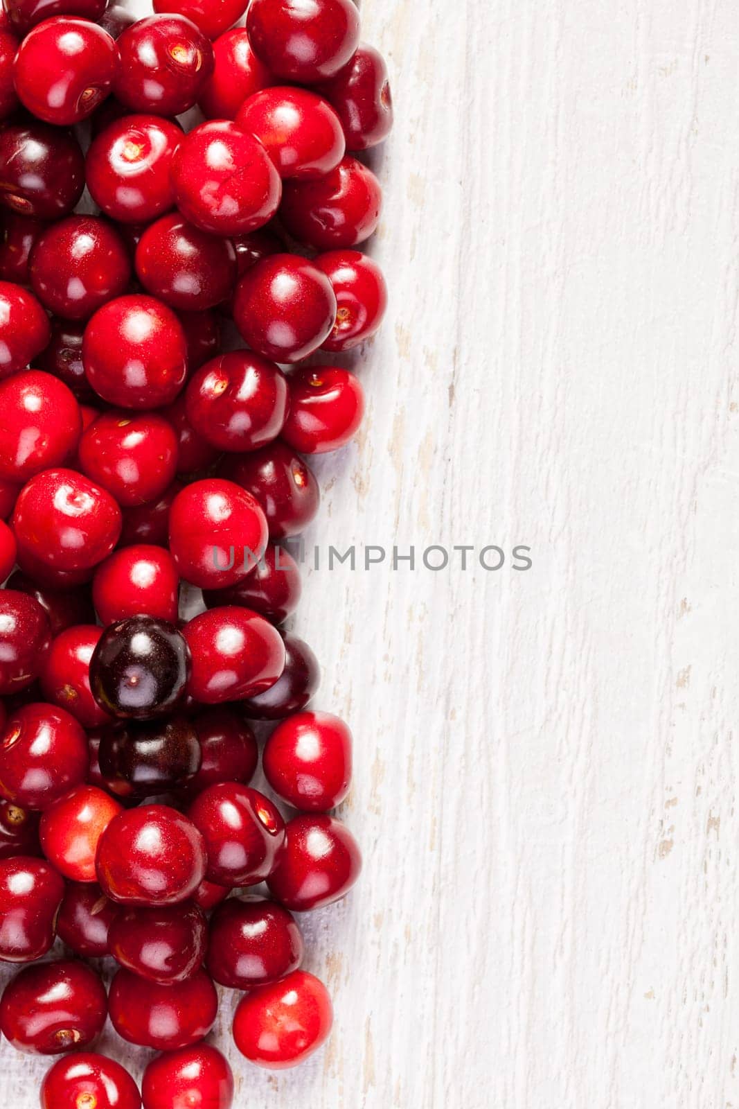 Delicious cherries on white wooden background in close up photo with copyspace available