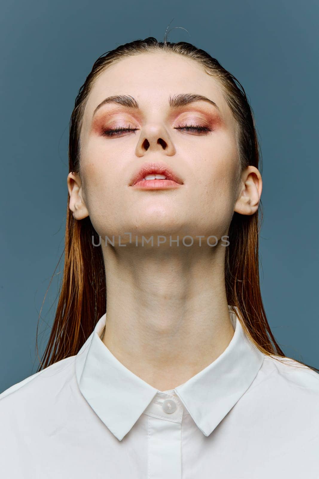 a close vertical portrait of a beautiful woman with her hair laid back, neat evening makeup, standing with her eyes closed. A photo from the fashion world without retouching by Vichizh