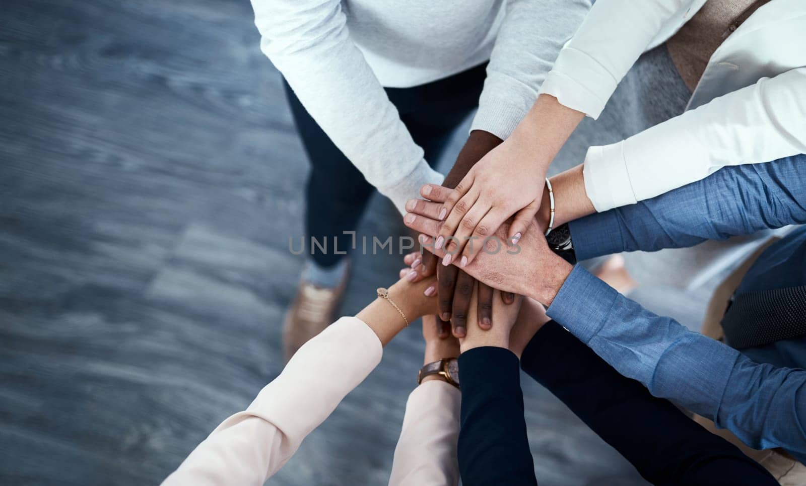 The secret is always teamwork. High angle shot of a group of unrecognizable businesspeople putting their hands together in a huddle. by YuriArcurs