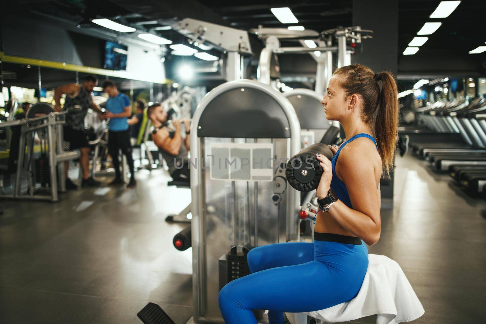 Shot of a muscular young woman in sportswear working out at the gym machine. 