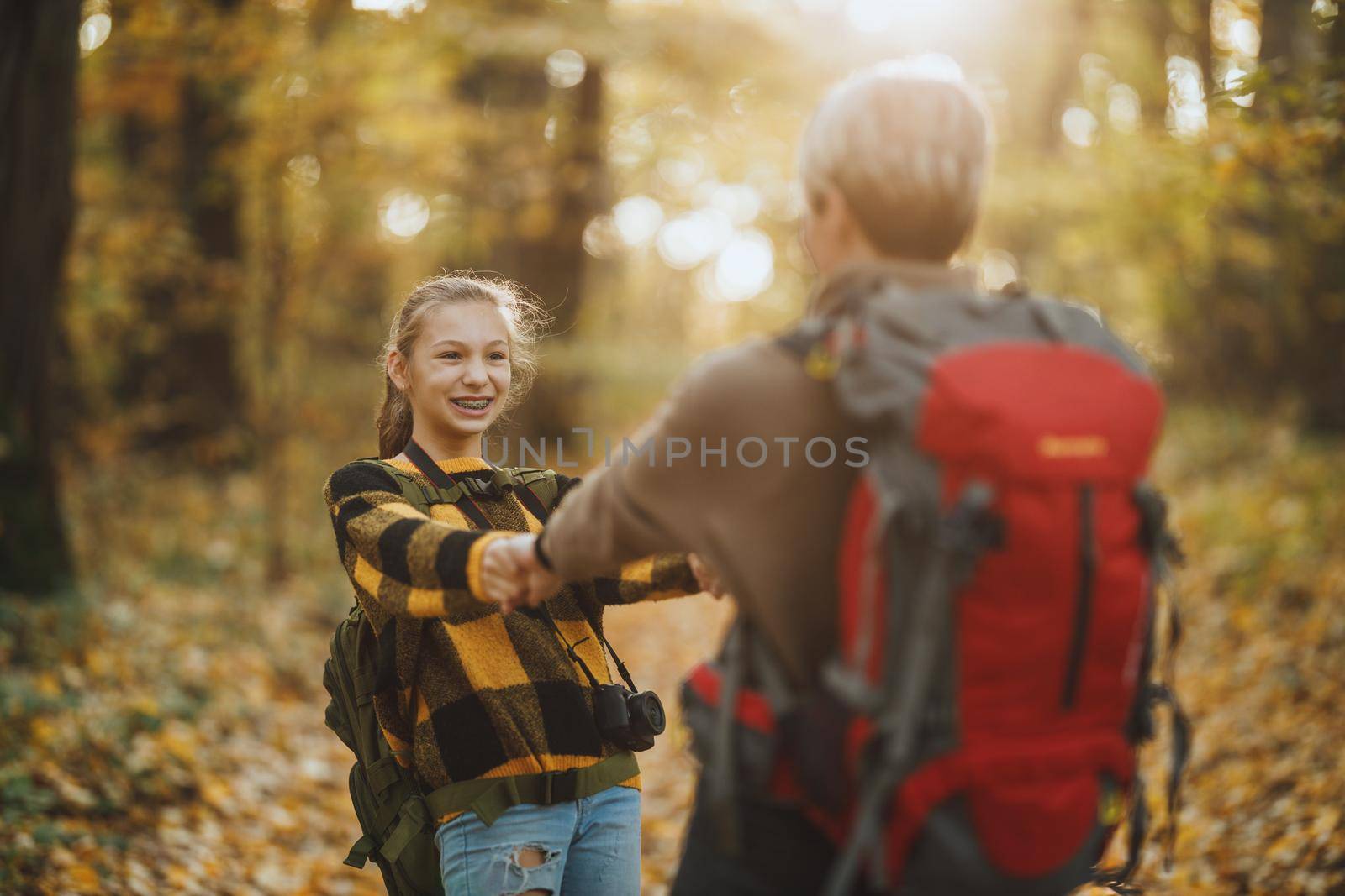 Shot of a teen girl and her mom having fund during walk together through the forest in autumn.