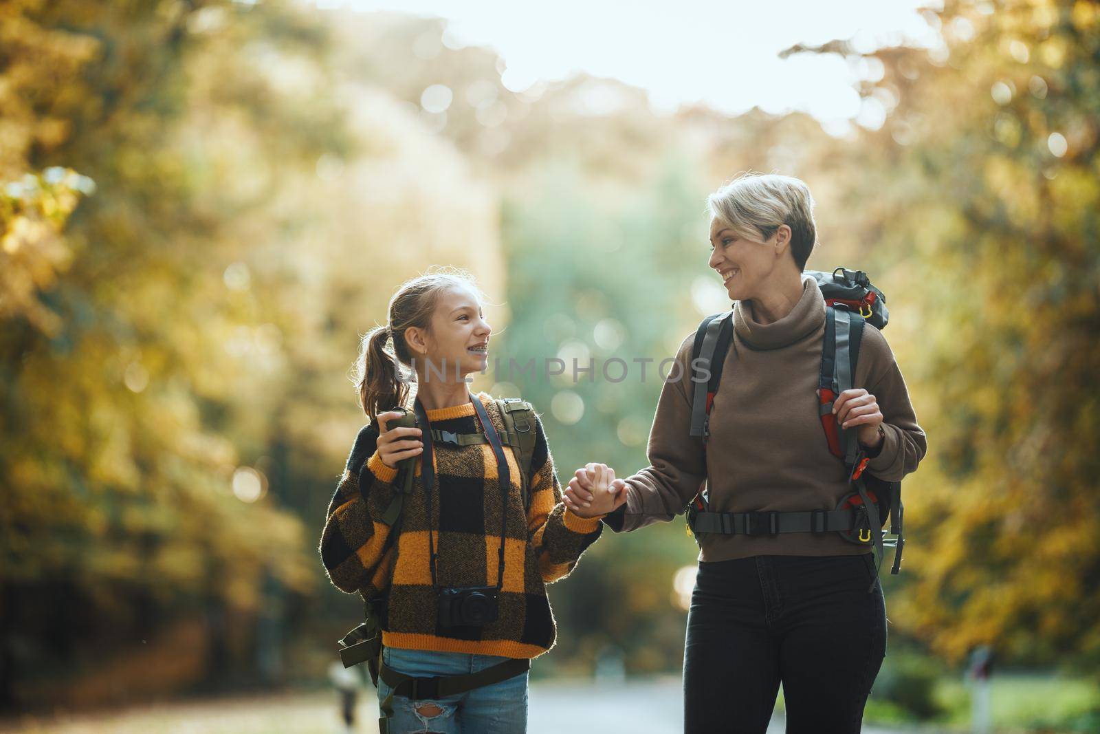 Shot of a teen girl and her mom walking together through the forest in autumn.