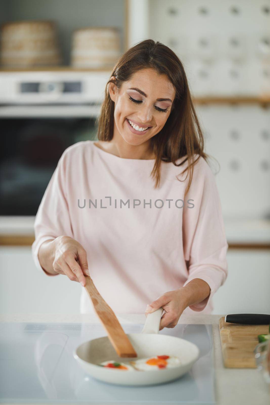 Shot of a young woman preparing a fried egg for breakfast in her kitchen.