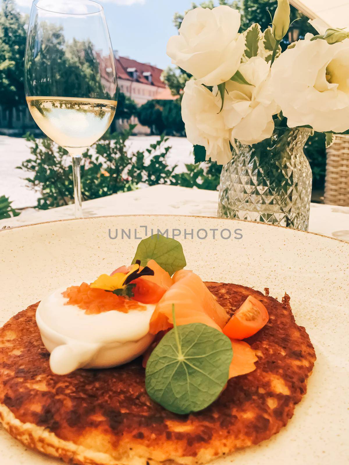 Potato fritter pancake with red caviar, salmon and sour cream in luxury restaurant outdoors in summer.