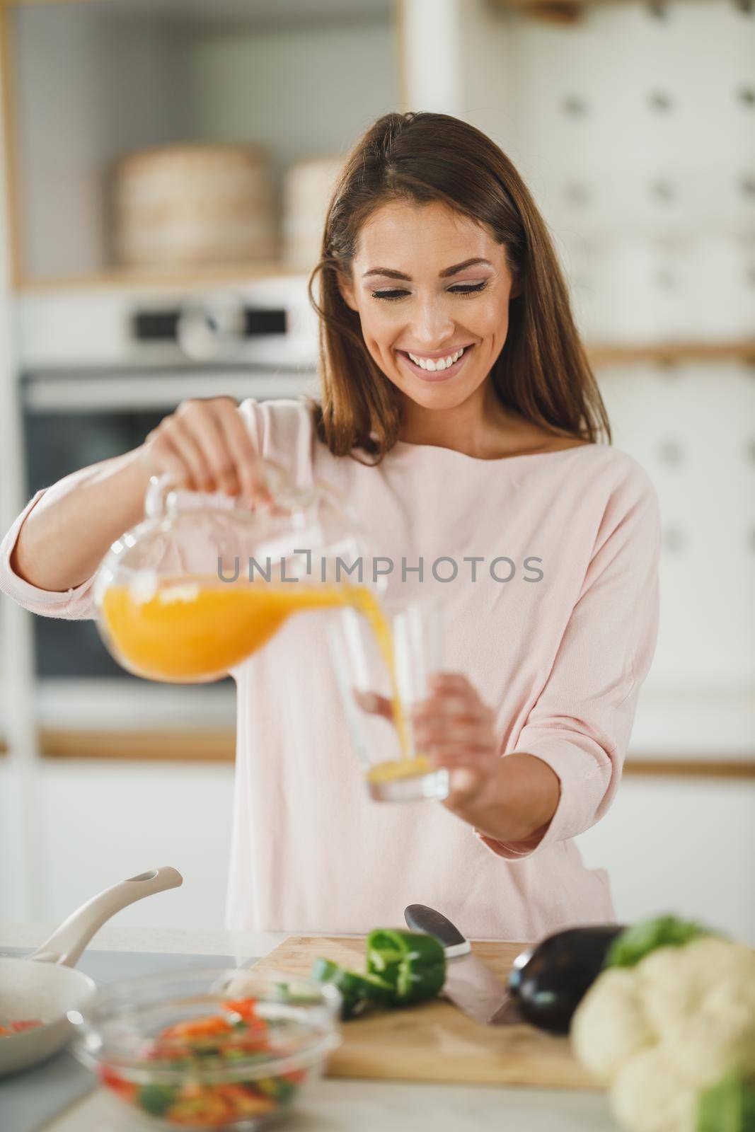 Shot of a young woman drinking fresh orange juice in her kitchen.