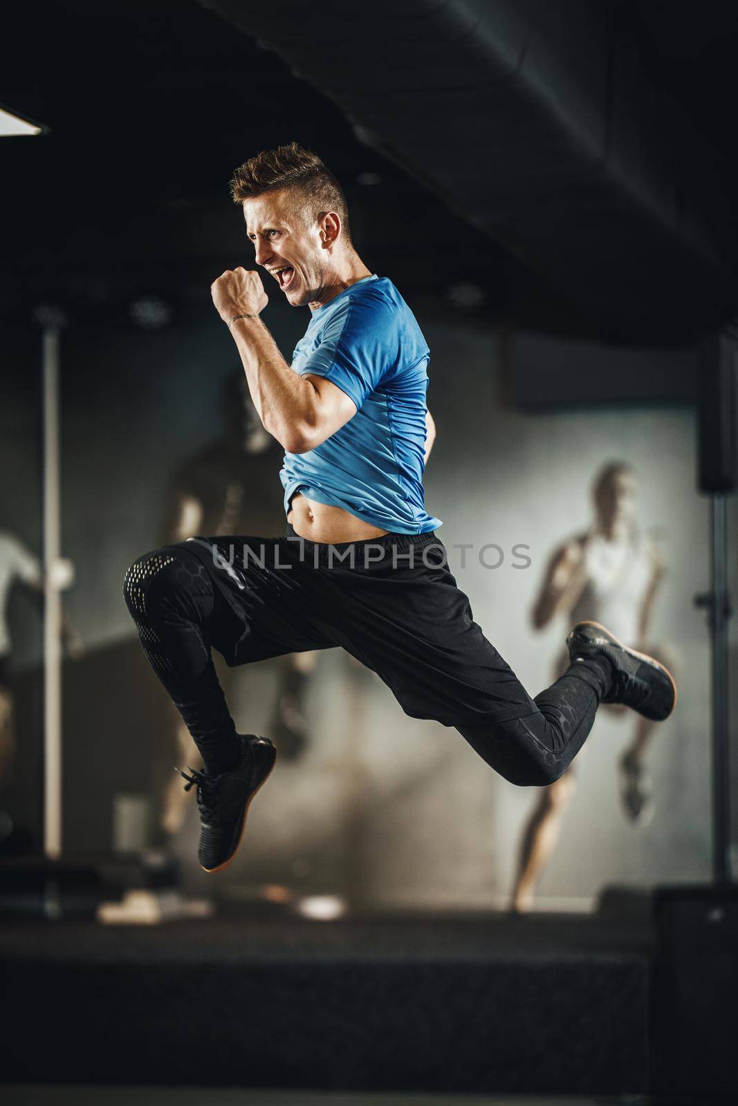 Shot of a handsome muscular guy in sportswear jumping mid air during working out at the gym.