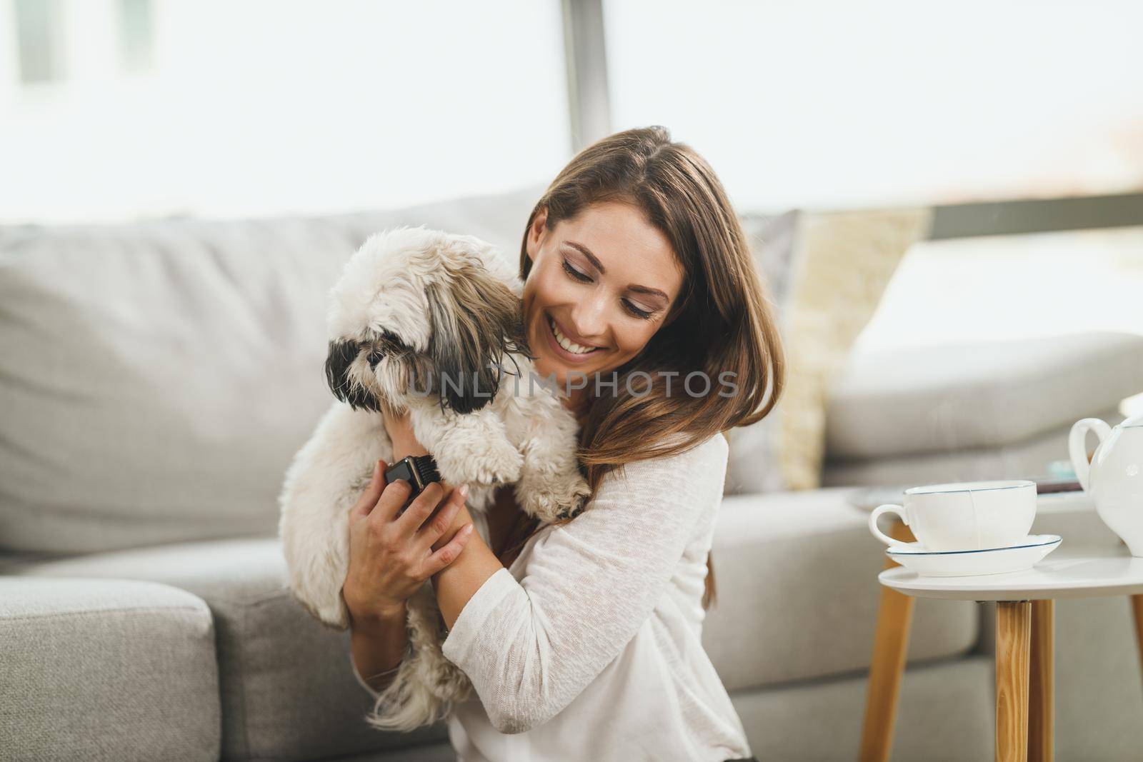 Shot of a cute young woman relaxing with pet dog in her living room at the home.