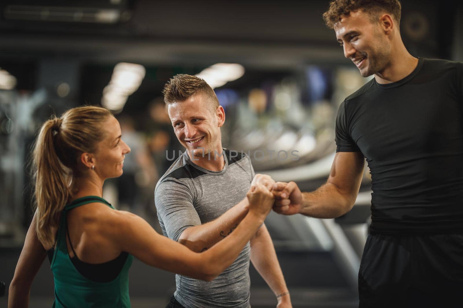 Shot of three young people joining their fists together in solidarity at a gym.