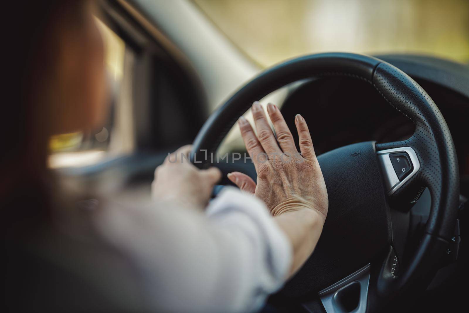 Cropped shot of a businesswoman pressing the hooter while driving a car.