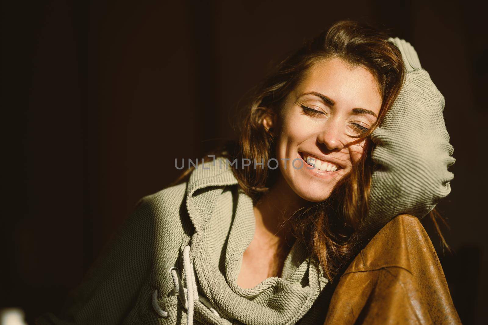 A cheerful young woman with closed eyes relaxing and enjoying a sunny morning.