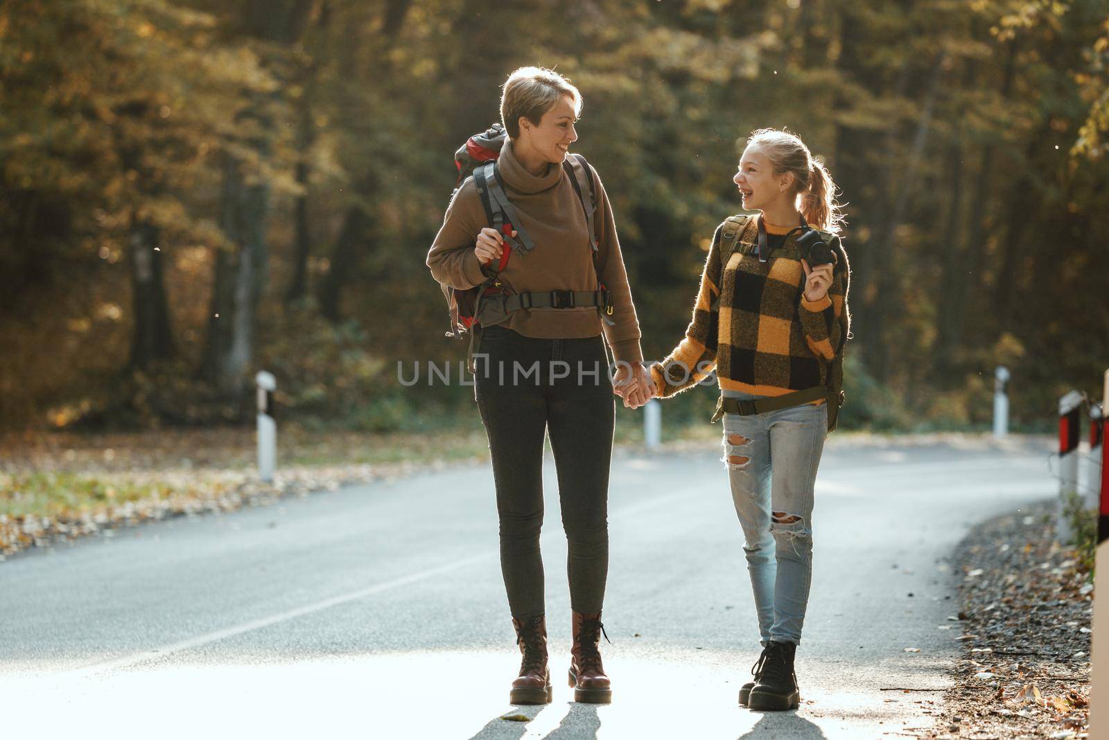Shot of a teen girl and her mom walking together through the forest in autumn.