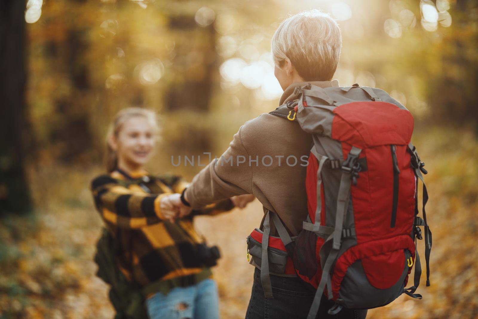 Shot of a teen girl and her mom having fund during walk together through the forest in autumn.