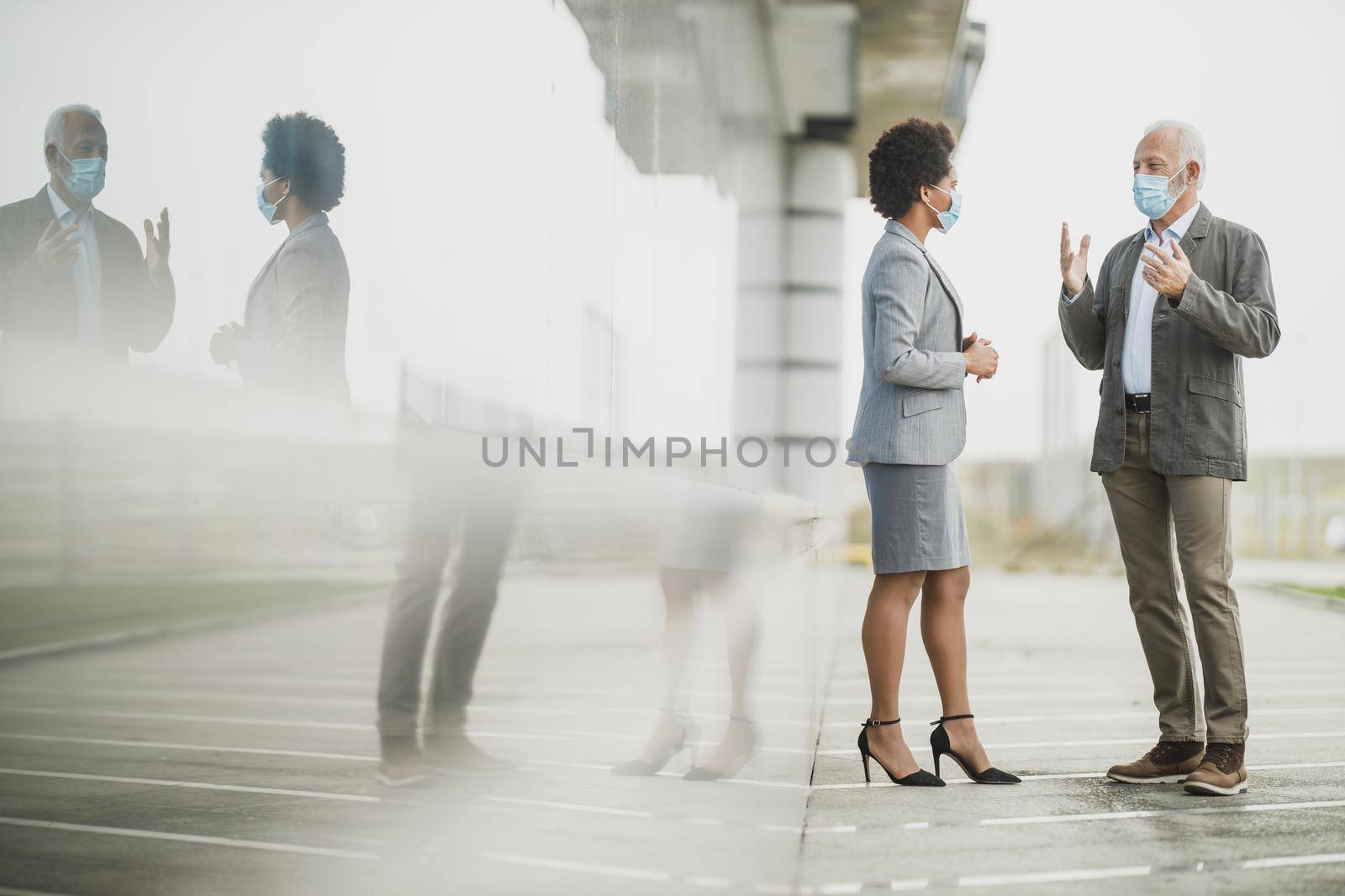 Shot of two successful multi-ethnic business people with protective mask having a discussion in front of the office building during COVID-19 pandemic.