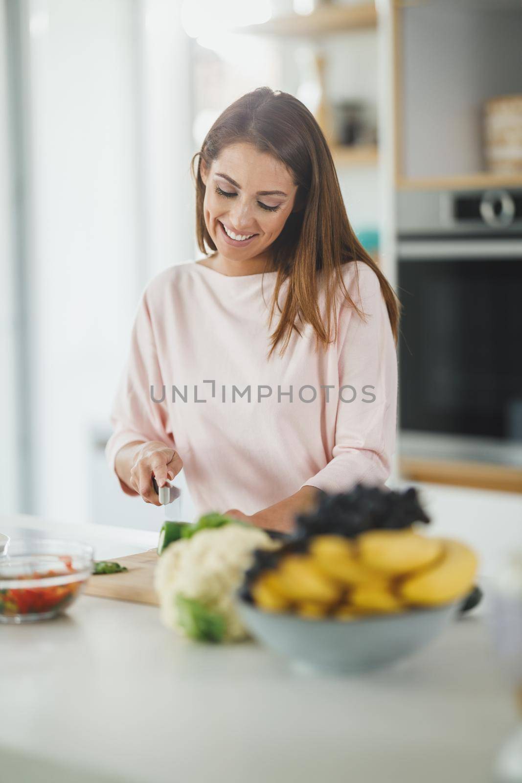 Shot of a young woman chopping vegetables and preparing a healthy meal in her kitchen.