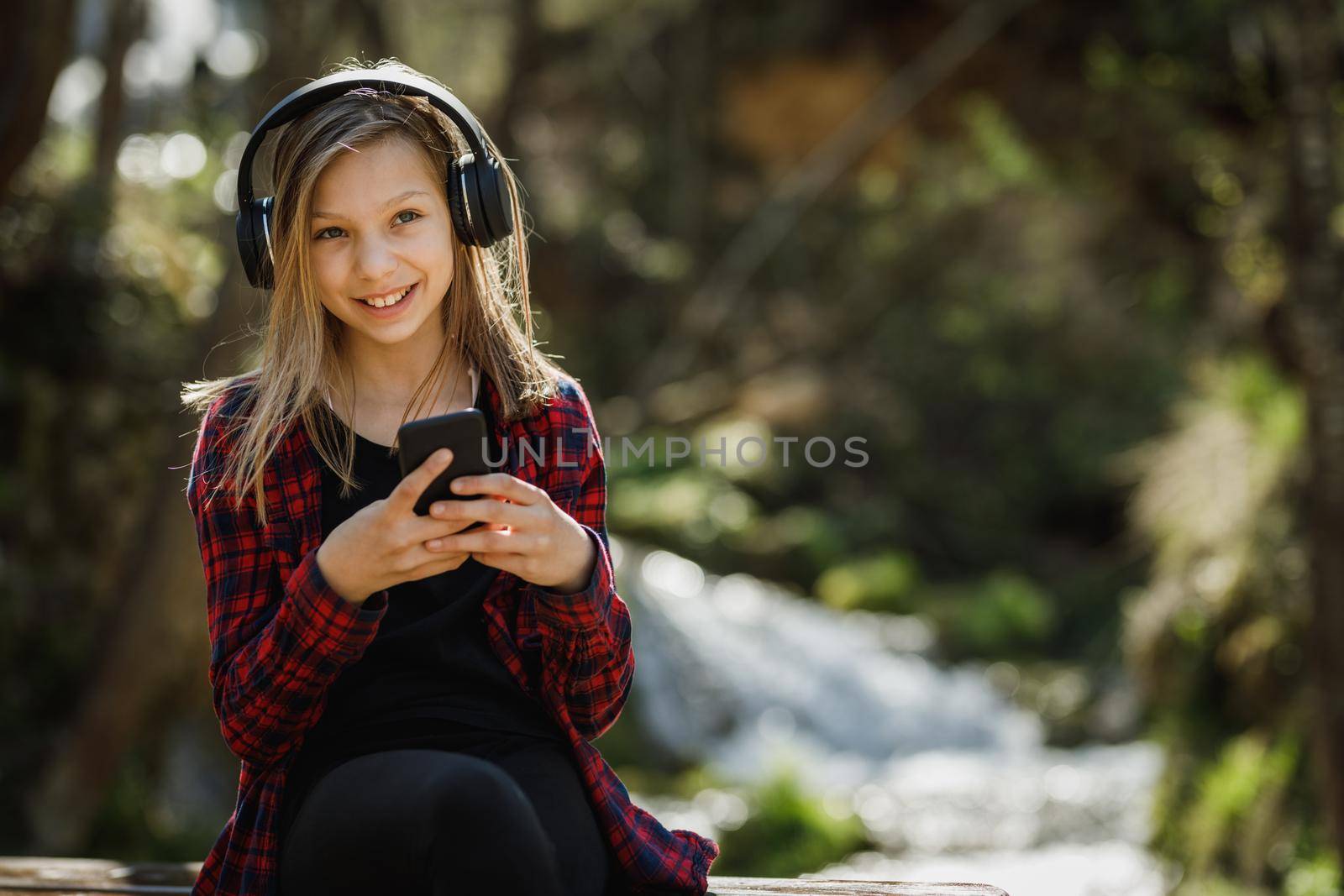 A carefree teenager girl listening music on her smartphone while enjoying the outdoors.