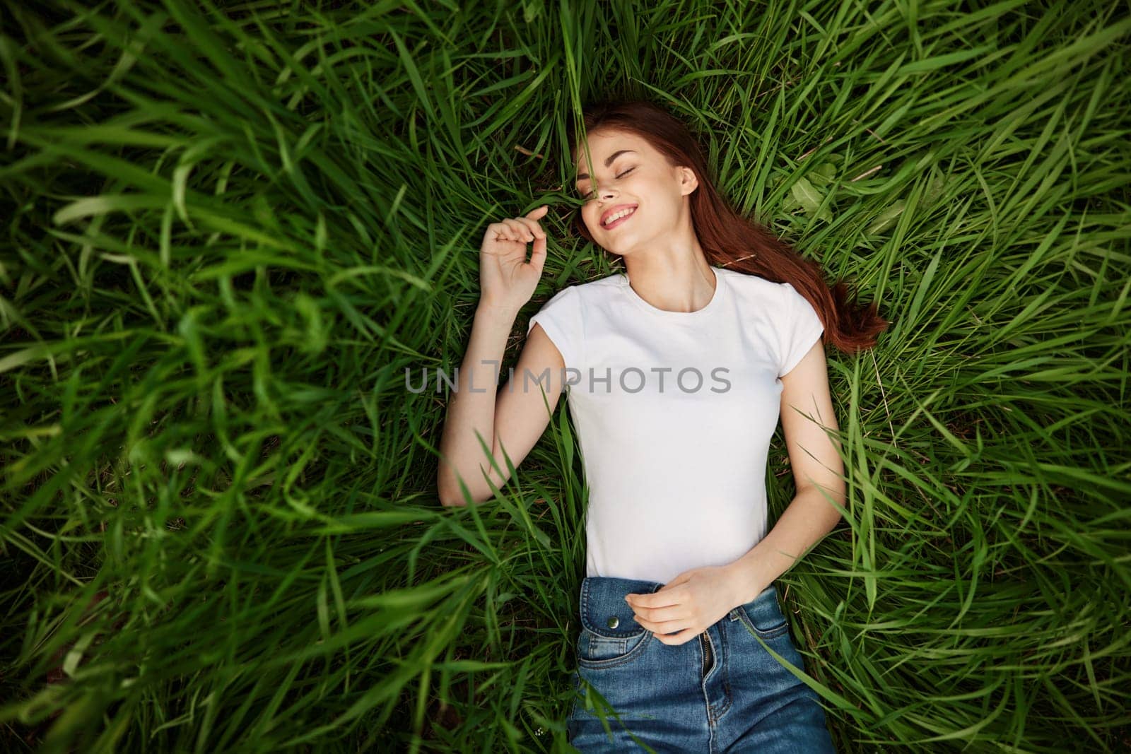 a woman lies in lush, green, tall grass. High quality photo