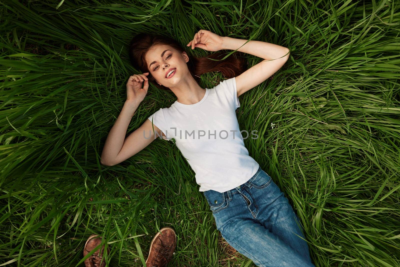 a woman lies in the tall grass with her eyes closed. High quality photo