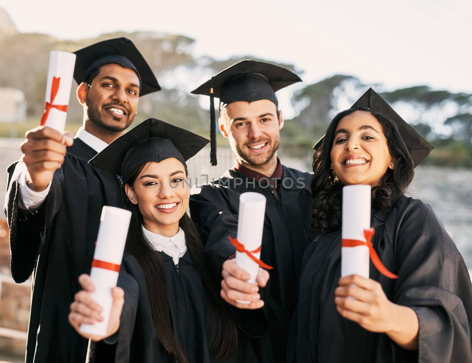 Heres looking to a bright new future. Portrait of a group of students celebrating with their diplomas on graduation day