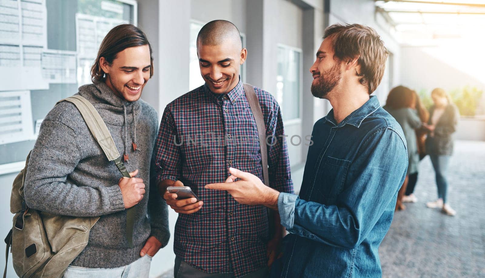 Theres always time for one more meme. a group of young students using a smartphone together outdoors on campus