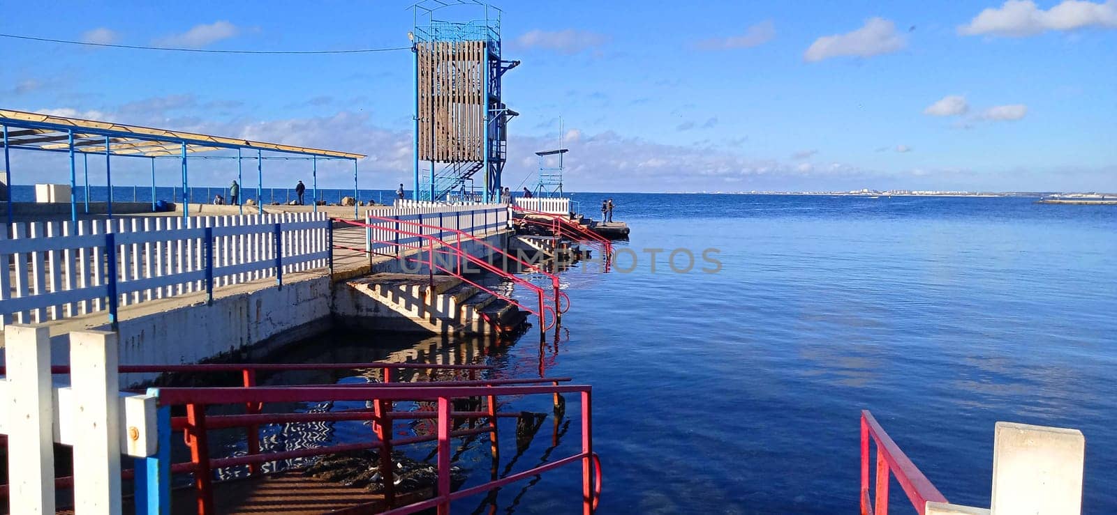 View of the sea and pier with lights at sunrise, blue sky without clouds