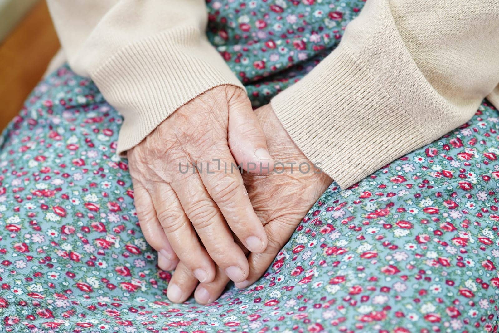 Asian elder senior woman patient sitting on bed in hospital, closeup at her hand. by sweettomato