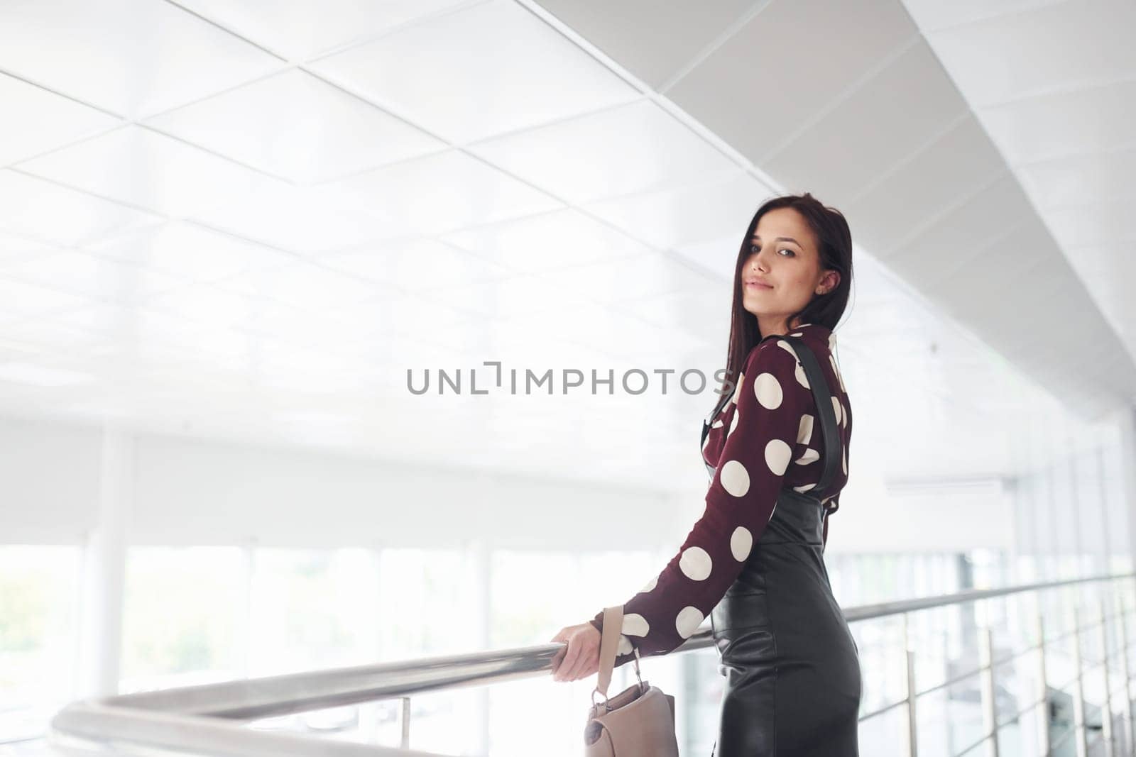 Beautiful young brunette in black skirt indoors in office or airport. Having free time by Standret
