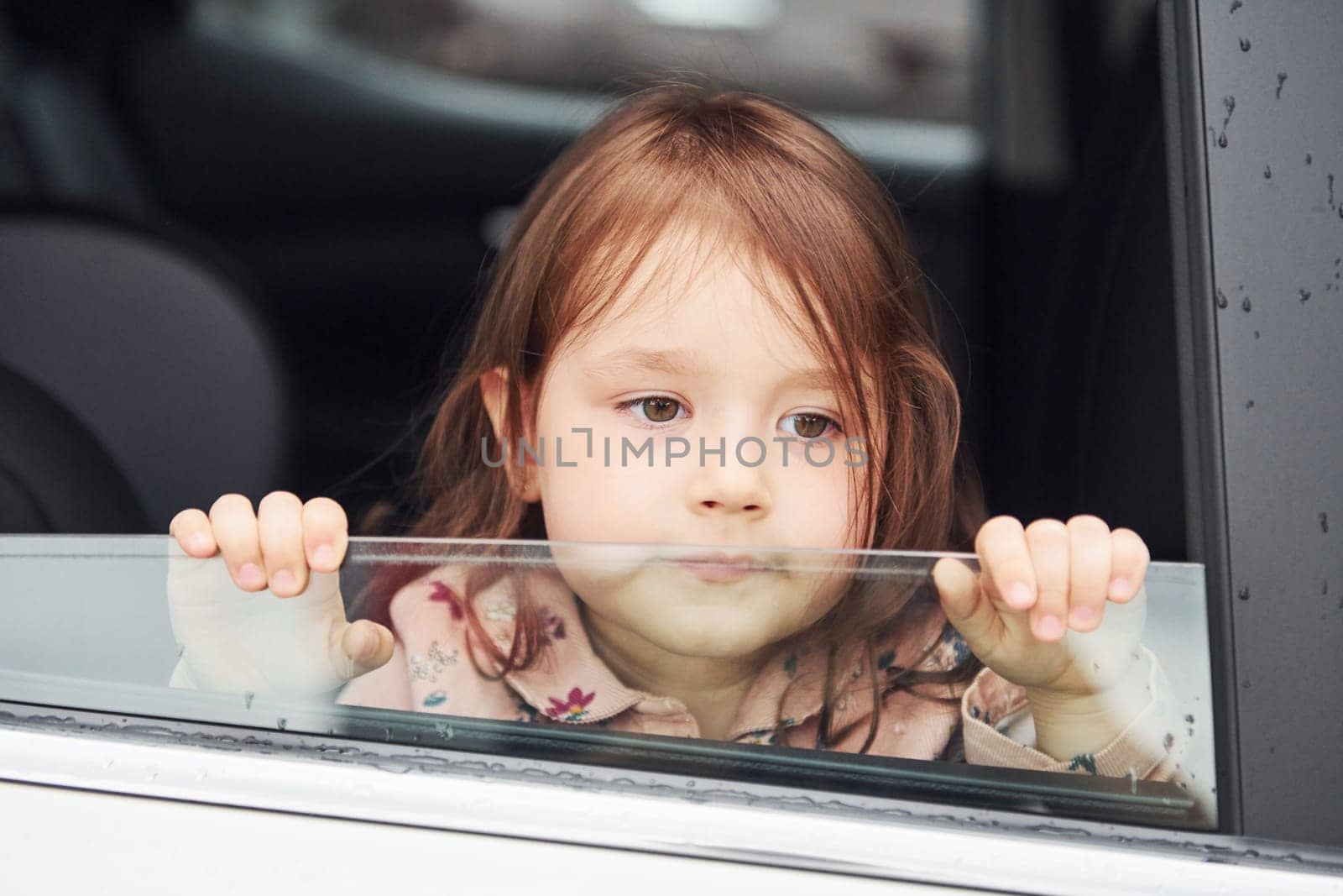 Cute little girl looks through window car. Conception of traveling and vaccation.