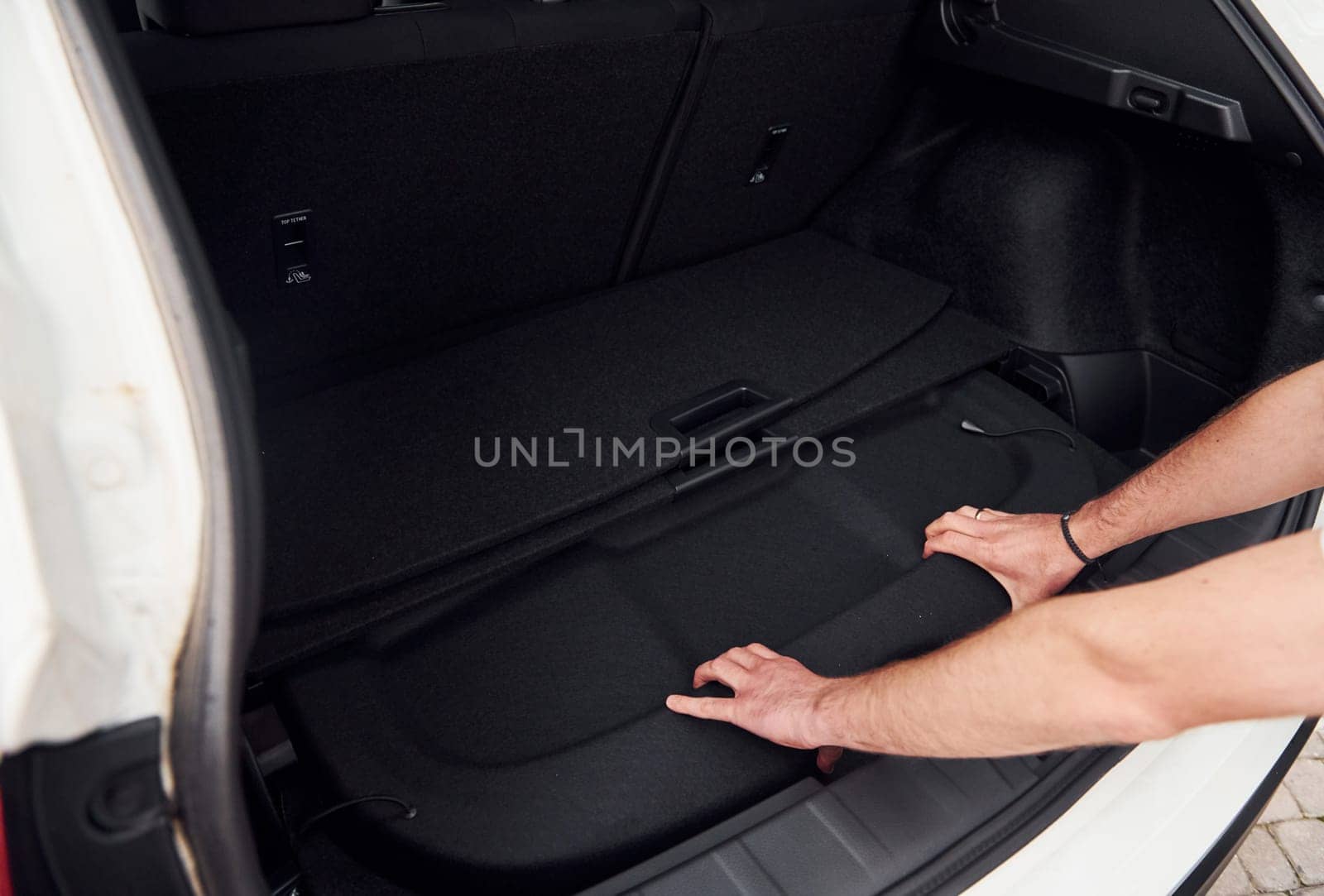 Woman's hands opening car trunk. Close up view. White modern automobile by Standret