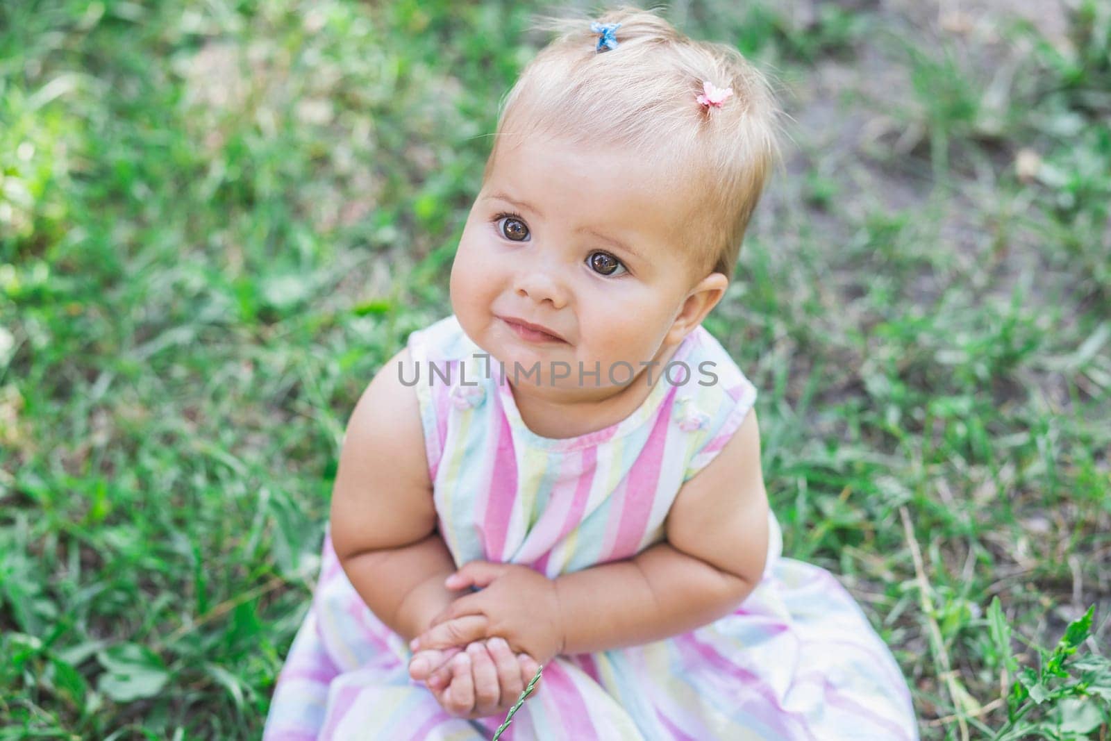 adorable baby in multicolored dress in the park.