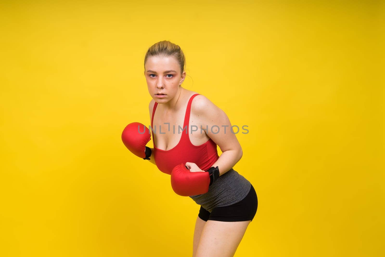 Image of a seductive young woman boxer posing isolated on yellow red background in boxing gloves. by Zelenin