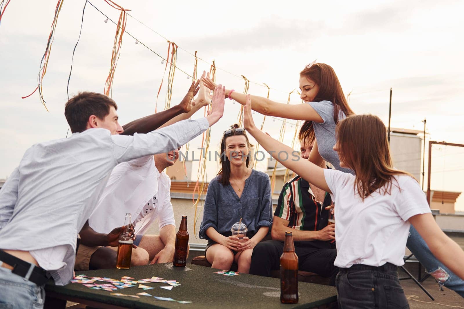 Unity of people. Group of young people in casual clothes have a party at rooftop together at daytime.