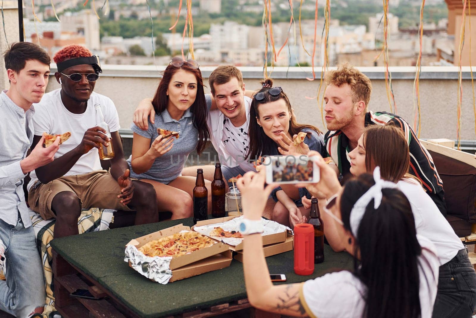 With delicious pizza. Group of young people in casual clothes have a party at rooftop together at daytime.