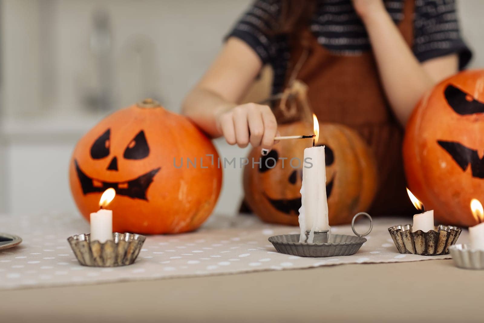 child girl lights a candle for Halloween. little girl in witch costume with carving pumpkin with a face made by child. Happy family preparing for Halloween. selective focus.