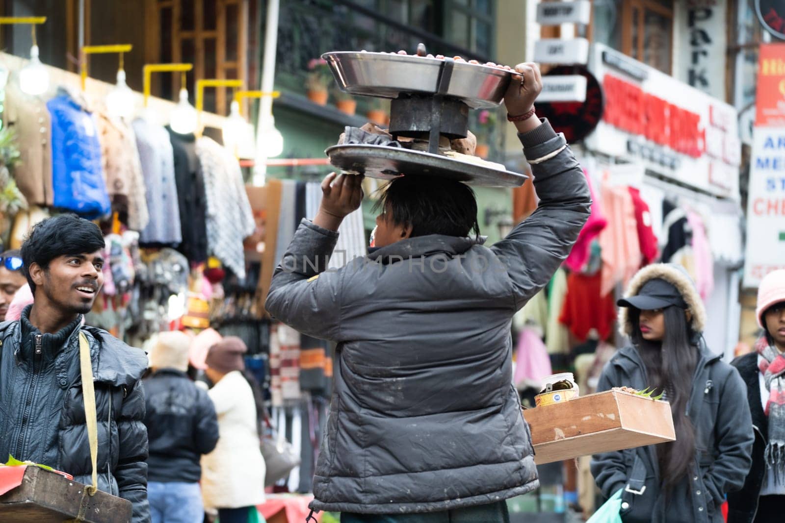 Manali, HImachal Pradesh, India - circa 2023 : Peanut and berry sellers with the food on their head talk to each other on the crowded mall road shimla