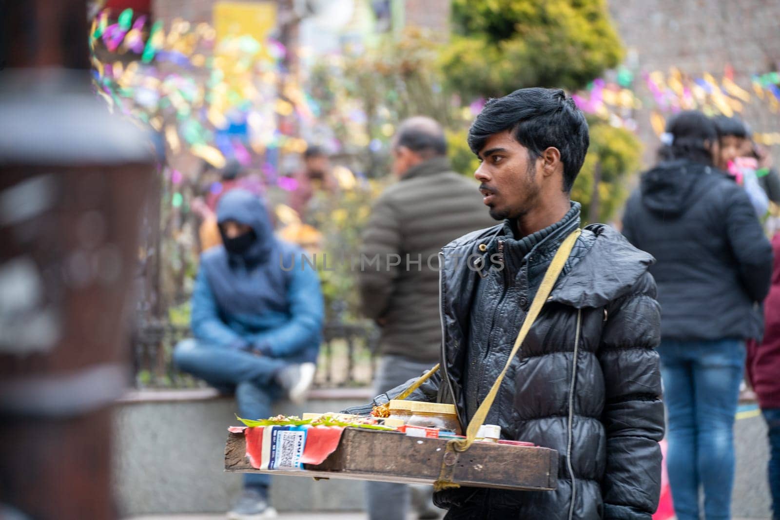 Manali, HImachal Pradesh, India - circa 2023 : Snack vendor with tray of street food around his neck looking for customers on mall road manali