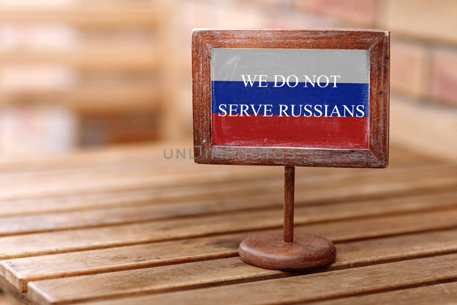 Empty wooden reserved plate on wooden table in a restaurant with text we do not serve Russians with flag of Russia.