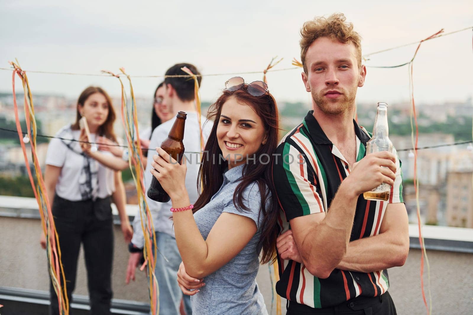 Happy couple. Group of young people in casual clothes have a party at rooftop together at daytime.