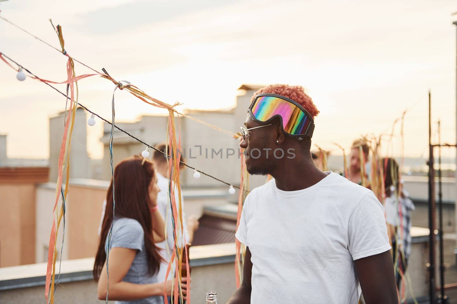 Posing for a camera. Group of young people in casual clothes have a party at rooftop together at daytime.