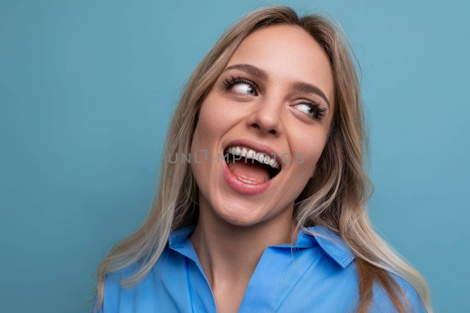 photo of an adorable young woman with a wide smile on a blue background.