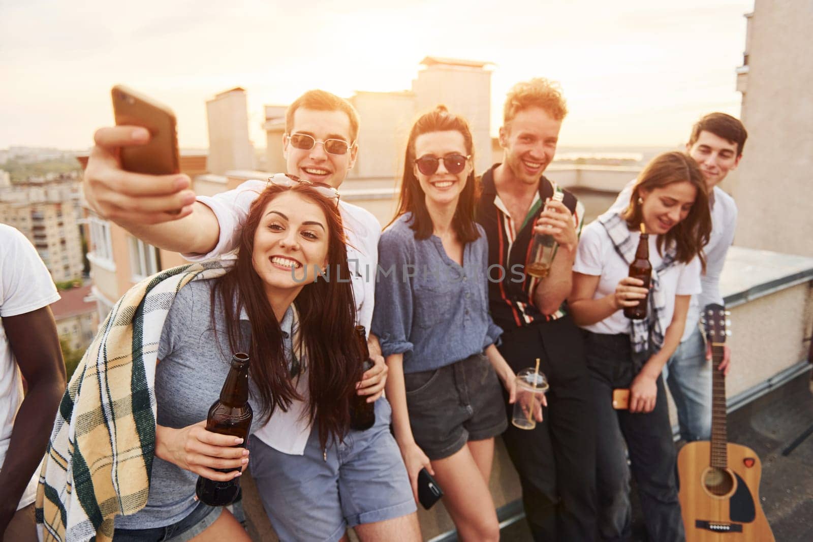 Taking selfie. Beautiful sunshine. Group of young people in casual clothes have a party at rooftop together at daytime.