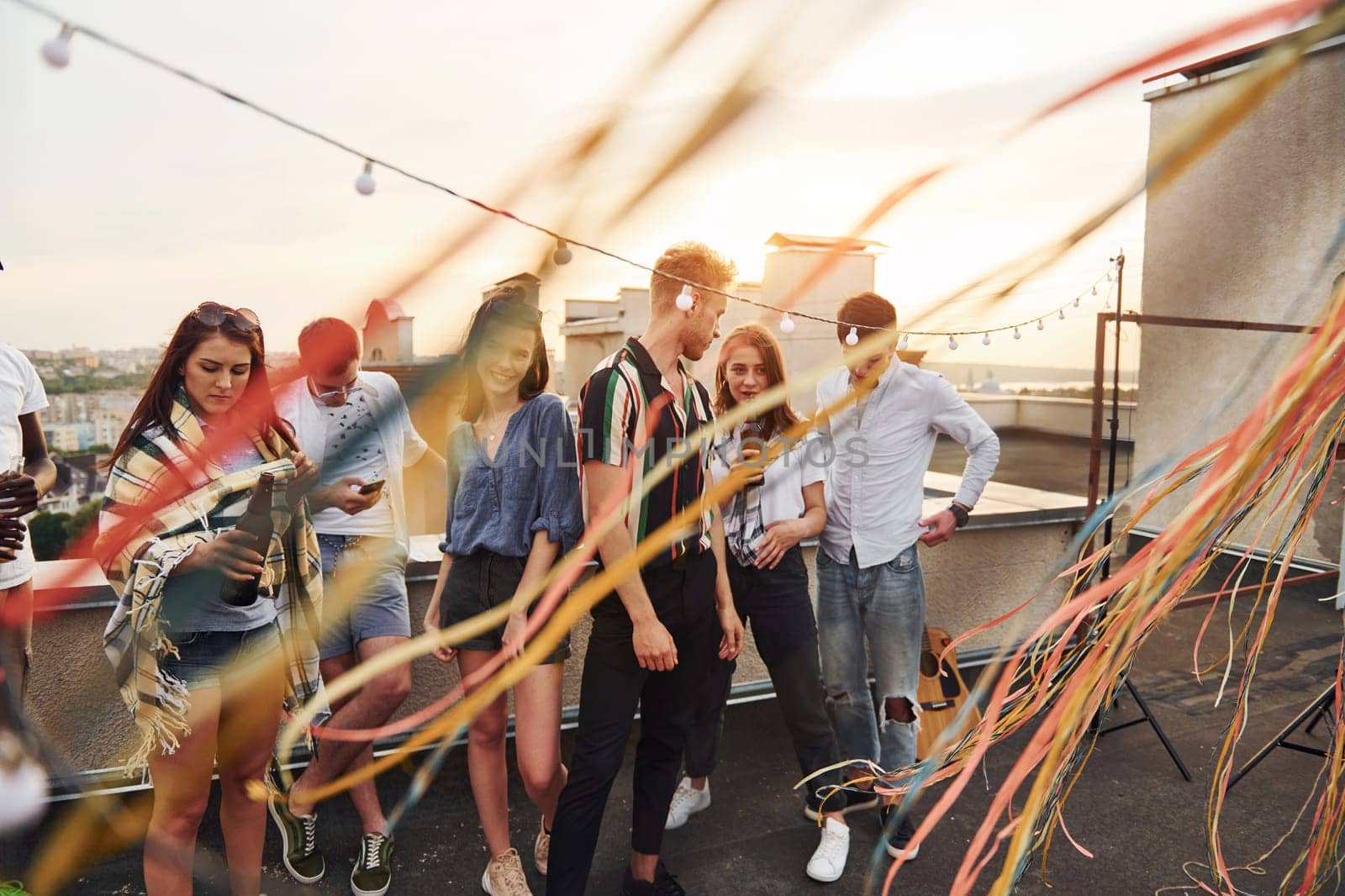 Group of young people in casual clothes have a party at rooftop together at daytime.