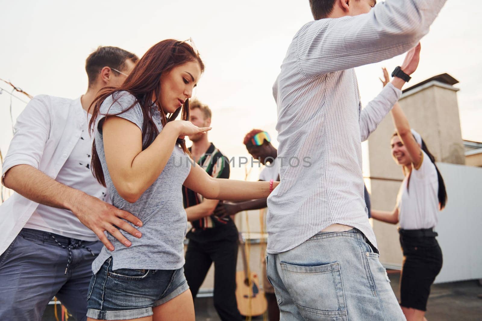 Recreation time. Group of young people in casual clothes have a party at rooftop together at daytime.